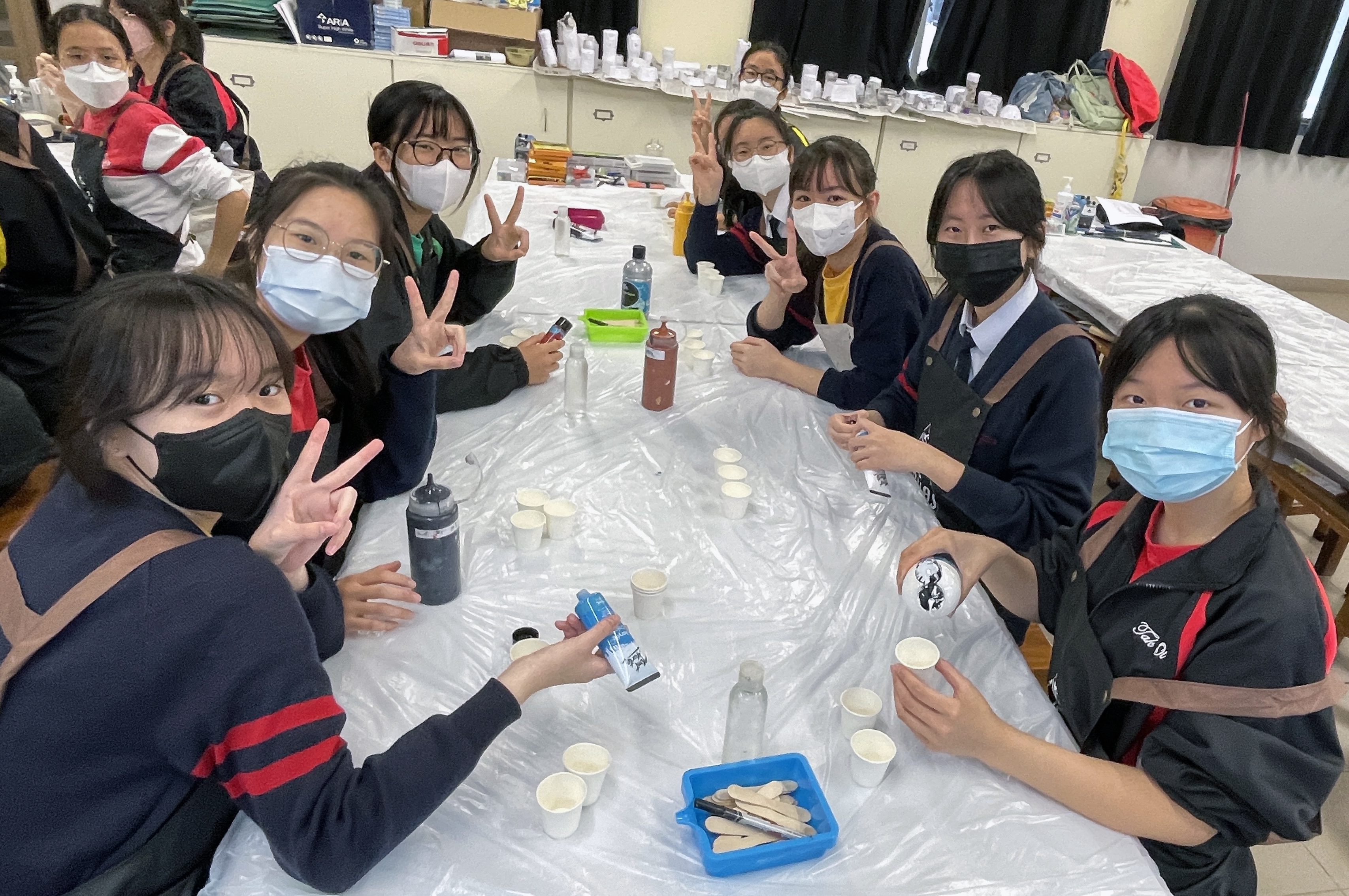 A group of people wearing face masks sitting at a tableDescription automatically generated