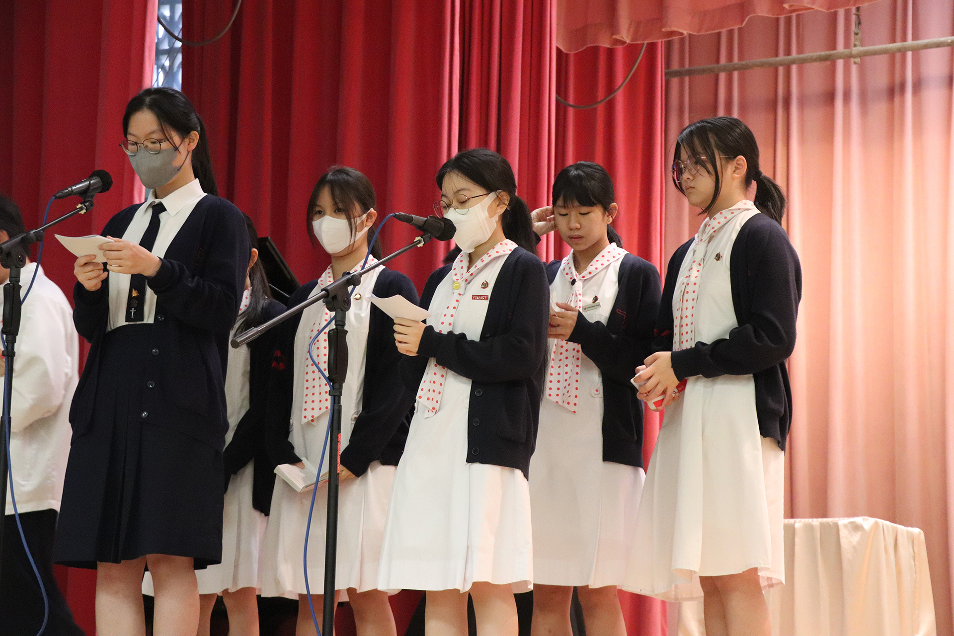 A group of girls wearing masks and standing in front of a statueDescription automatically generated