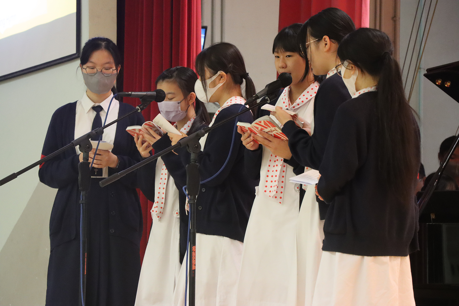 A group of girls wearing masks and standing in front of a statueDescription automatically generated