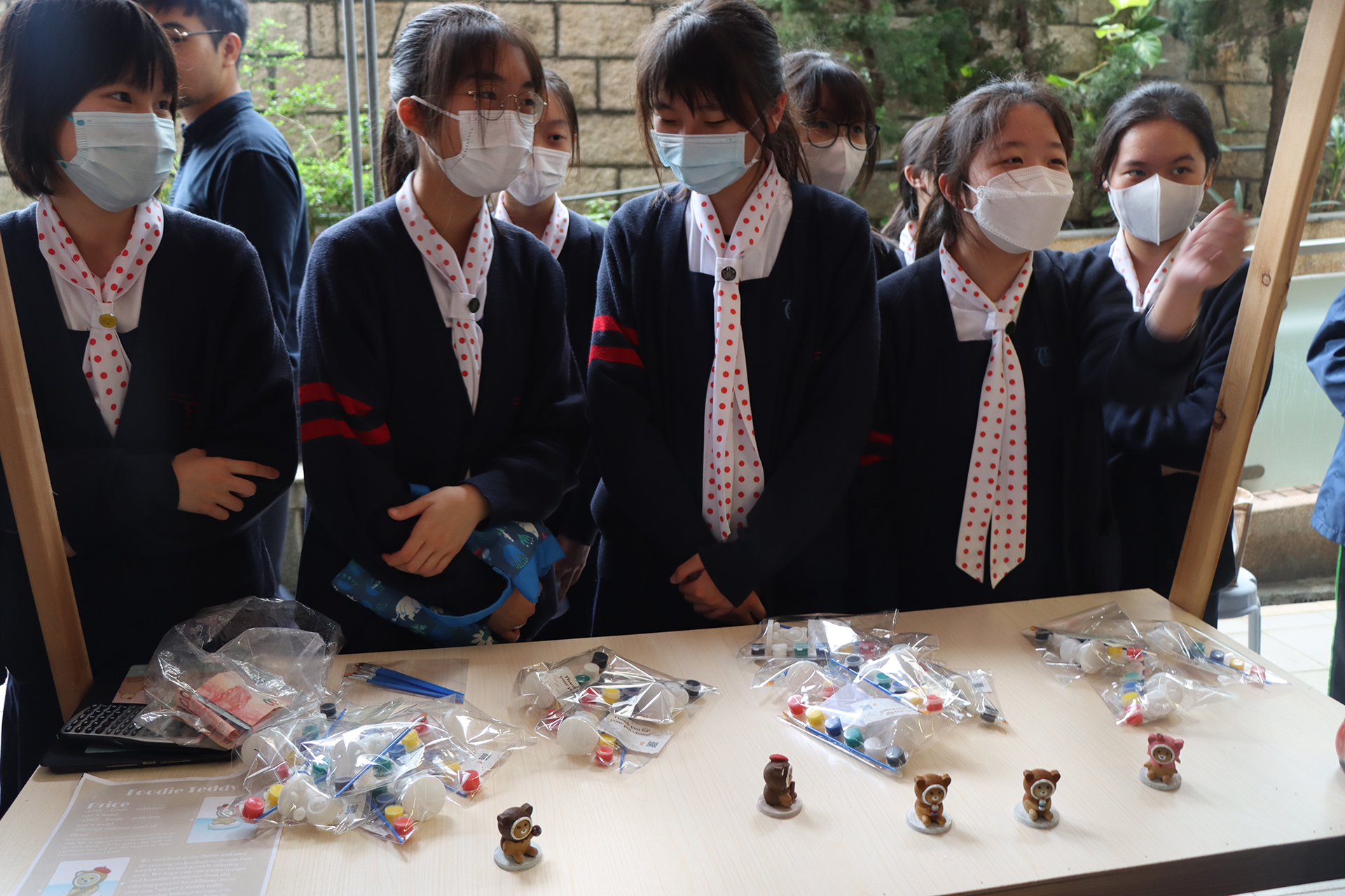 A group of girls wearing masks and standing in front of a statueDescription automatically generated