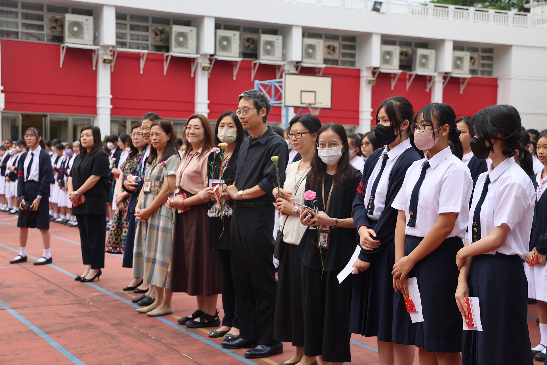 A group of girls wearing masks and standing in front of a statueDescription automatically generated