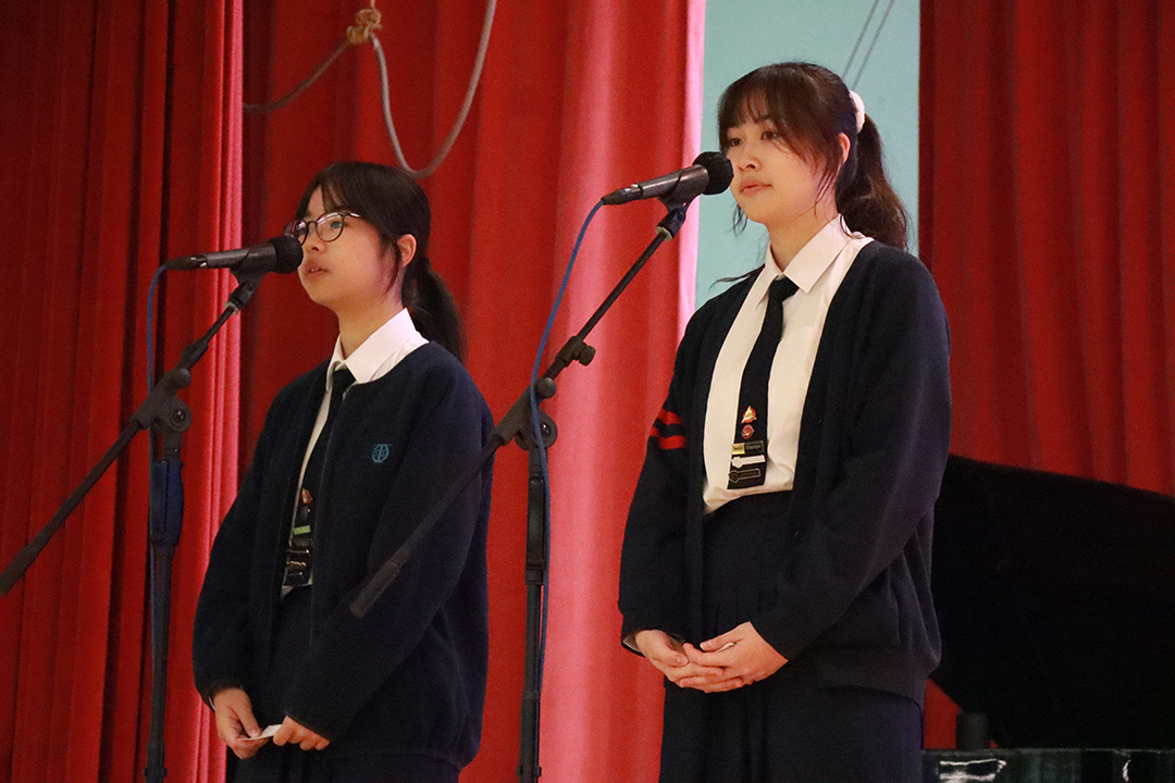 A person standing in front of a bannerDescription automatically generated
