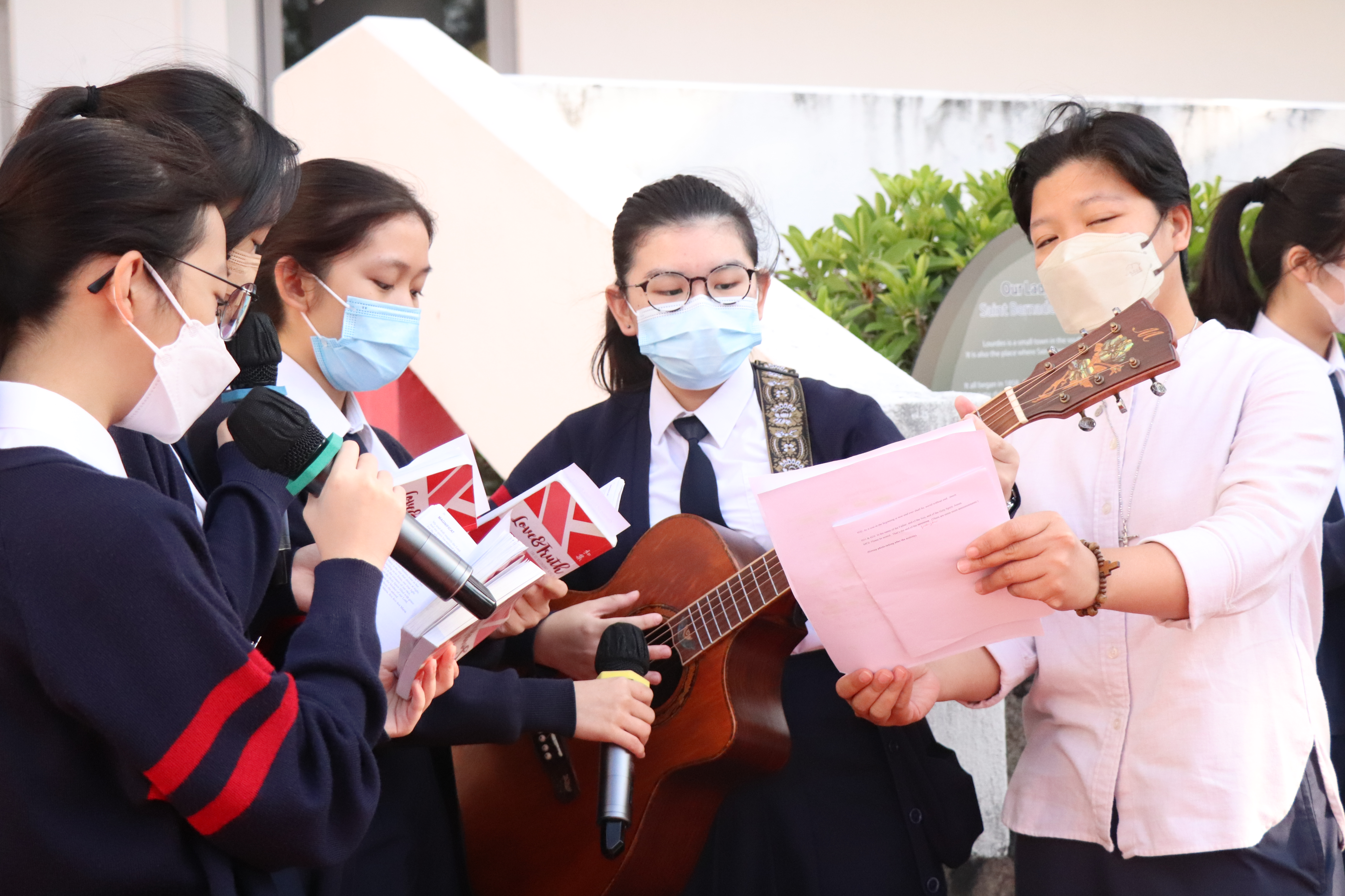 A group of people wearing face masks holding microphones and a guitarDescription automatically generated
