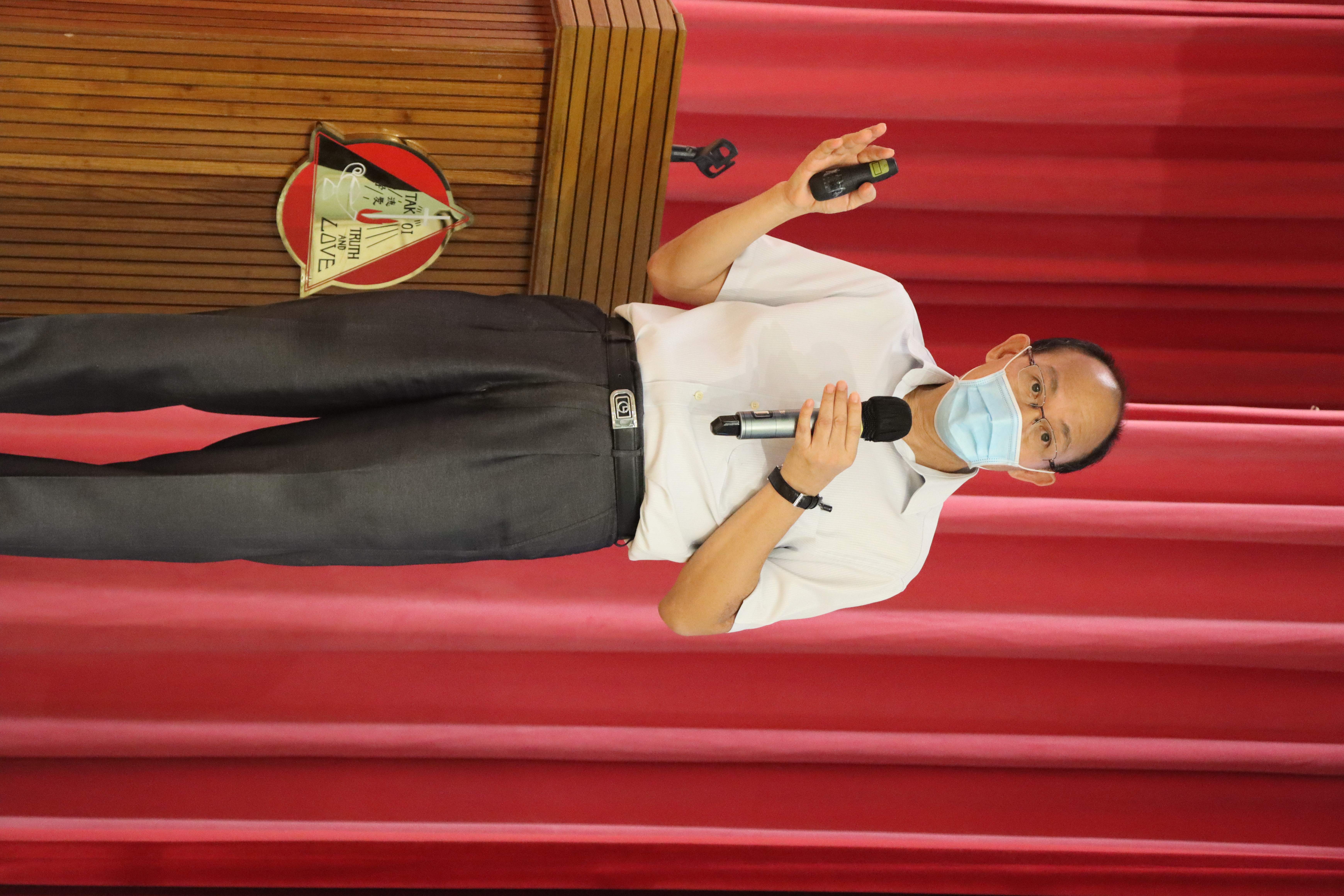 A person wearing a mask and holding a microphoneDescription automatically generated